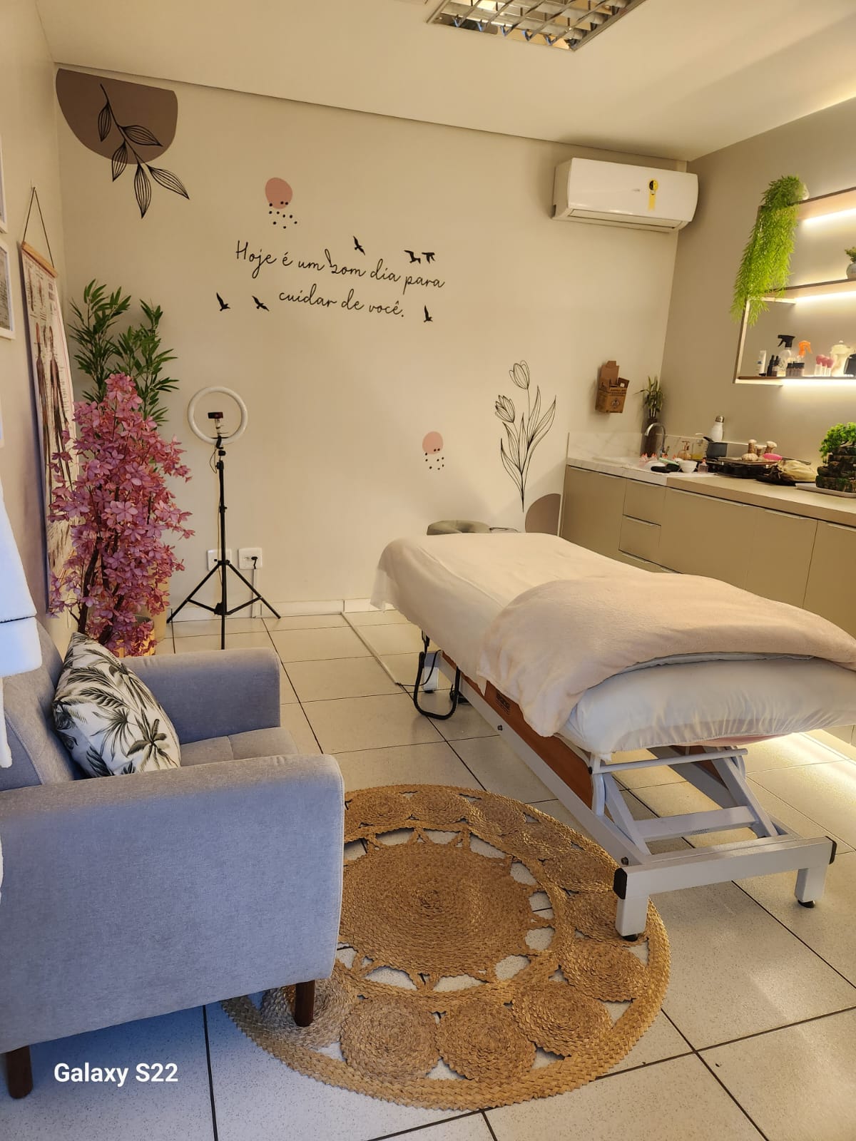 Espaço acolhedor com maca, decoração natural e parede com mensagem inspiradora